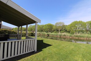 A covered outdoor area with a view of a pond and surrounding greenery.