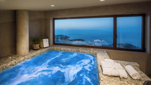 Un cuarto de spa con hidromasaje, toallas y vista al océano.