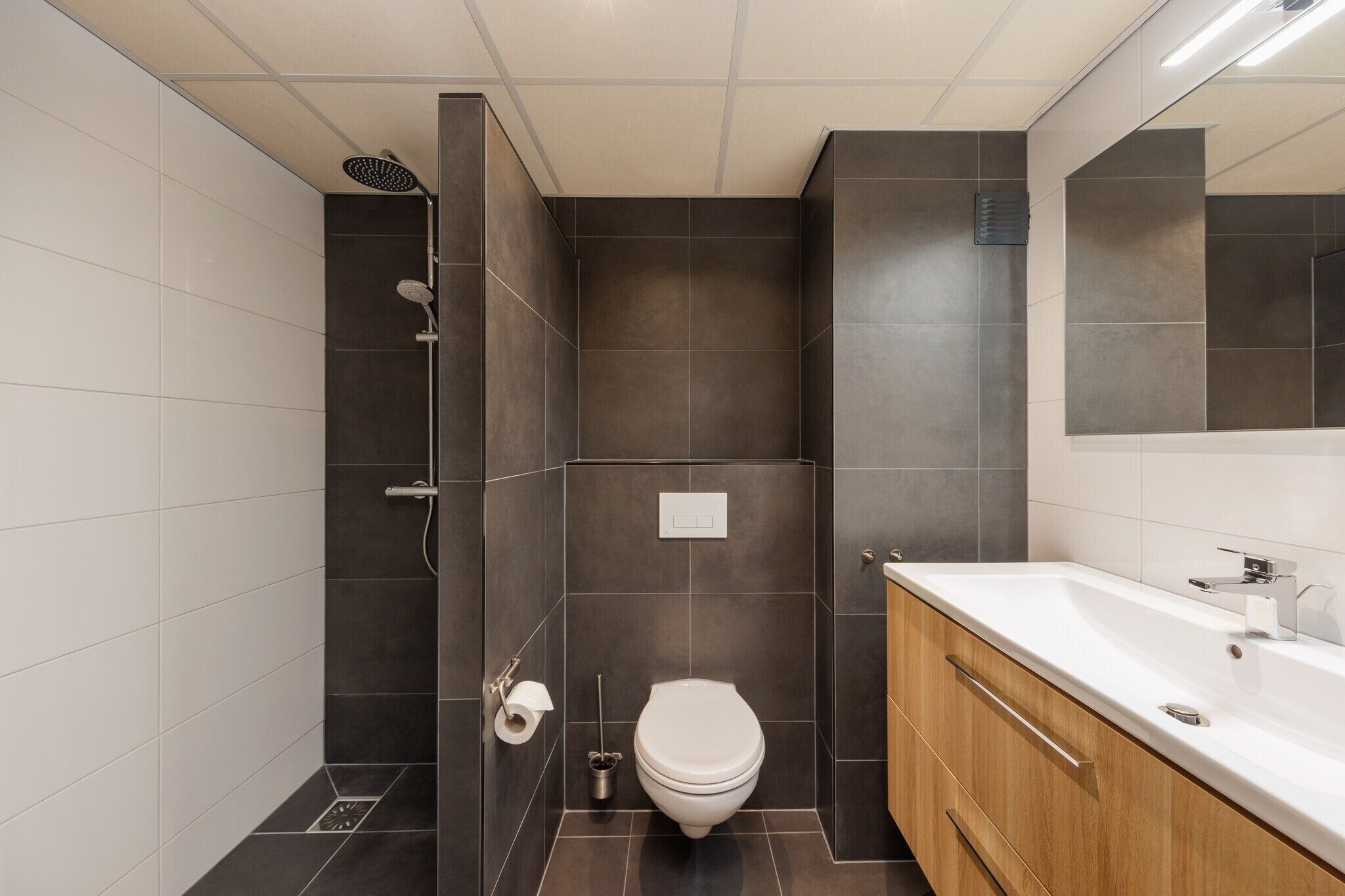 A modern bathroom with a shower, toilet, and sink.