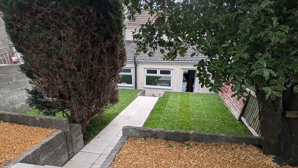 A residential property with a paved pathway leading to a house, a well-maintained lawn, and a stone retaining wall. - Gilfach Cynon Cottage - Beacons & BikePark (Merthyr Tydfil)