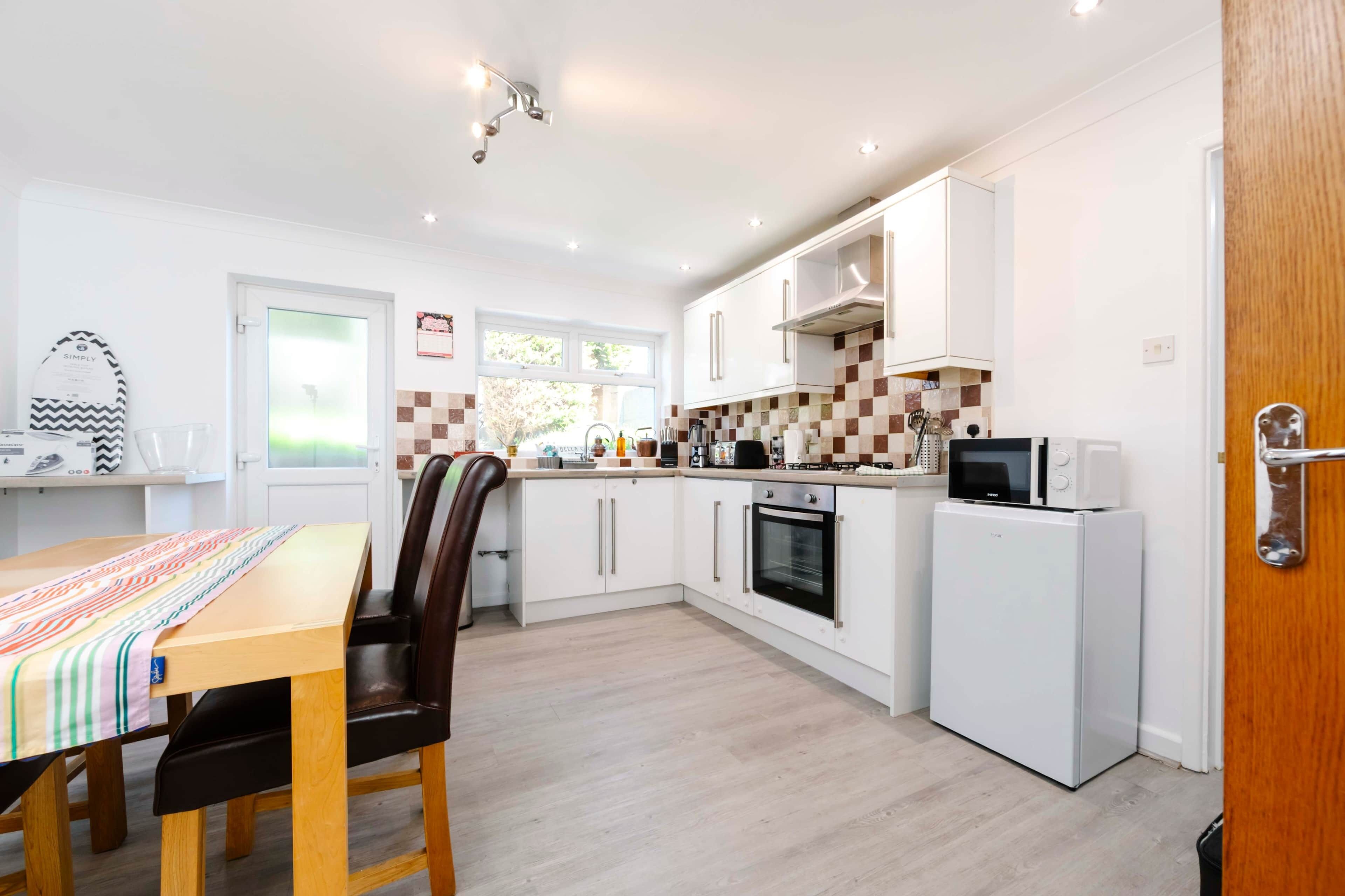 A compact kitchen with white cabinets, a microwave, an oven, and a refrigerator.