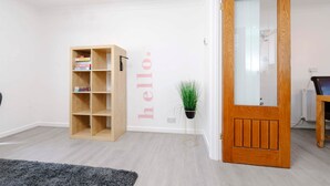 A room with a wooden bookshelf, a door with a mirror, and a small potted plant. - Gilfach Cynon Cottage - Beacons & BikePark (Merthyr Tydfil)