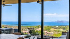 Ein Balkon mit Tisch, Stühlen und einer Sitzecke, der einen schönen Blick auf das Meer und die Landschaft bietet.