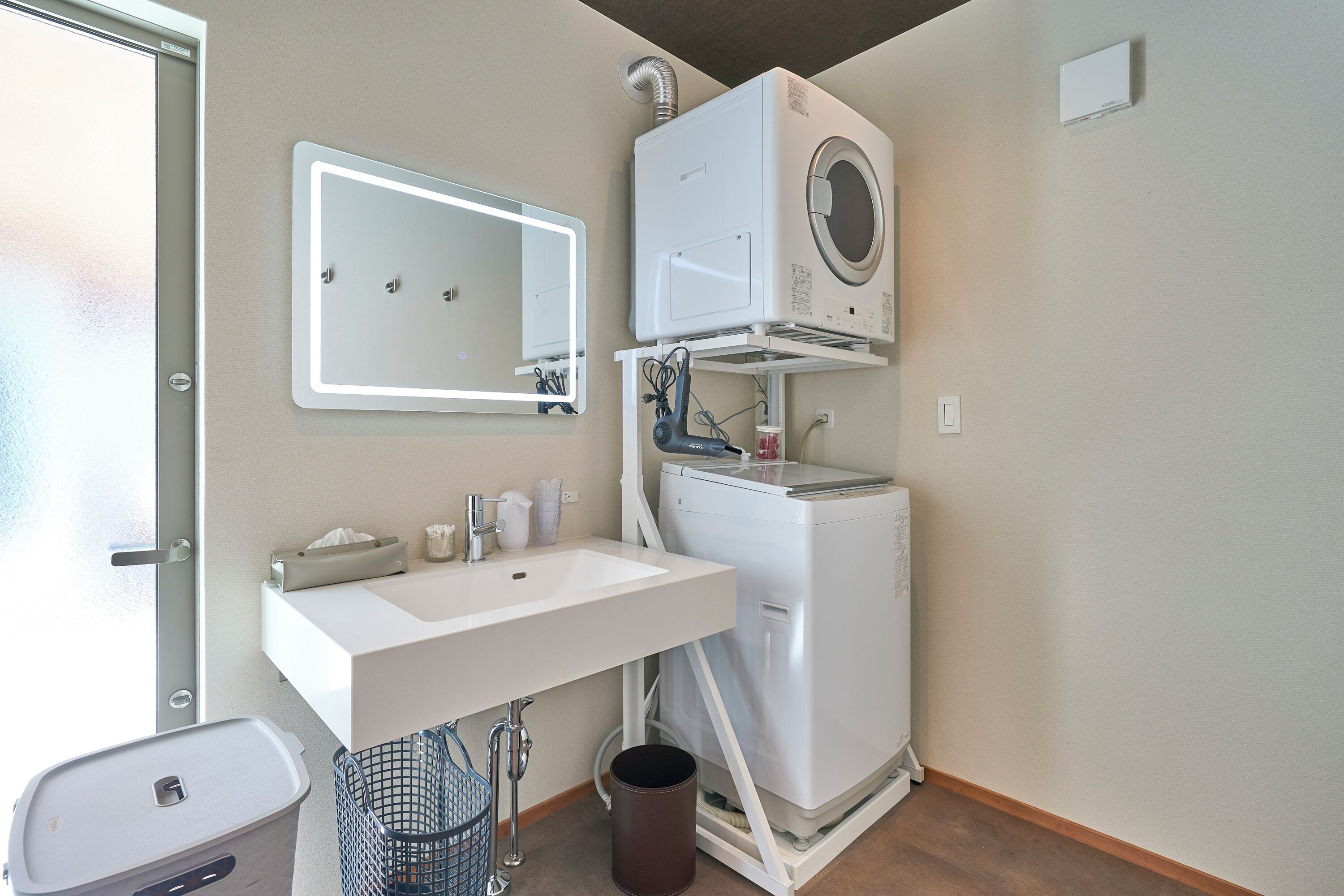 A compact bathroom with a white sink, mirror, and a compact washer-dryer unit.