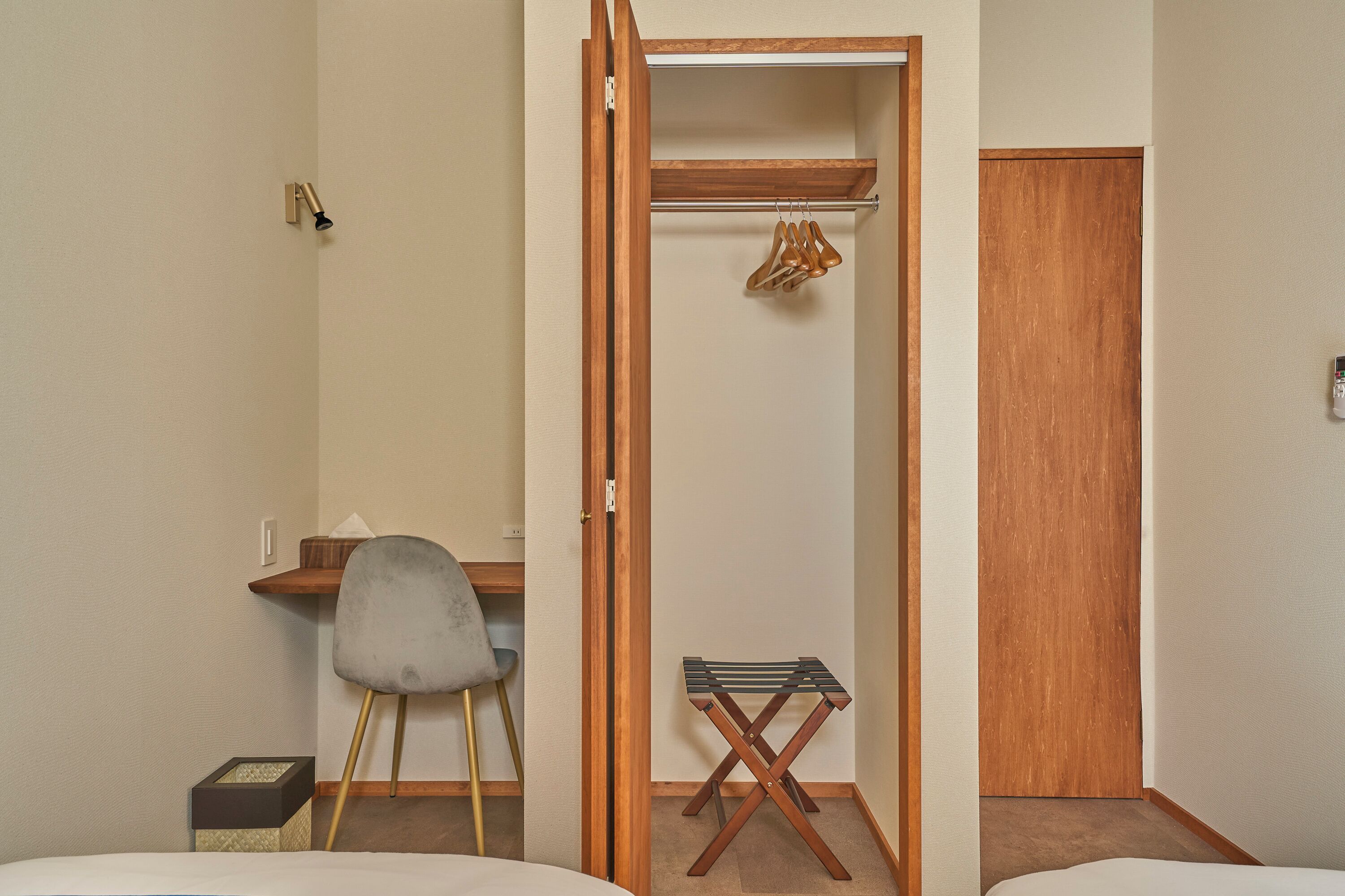 Une chambre d’hôtel comprenant un lit, un bureau avec une chaise, une armoire en bois et une petite table avec une chaise.