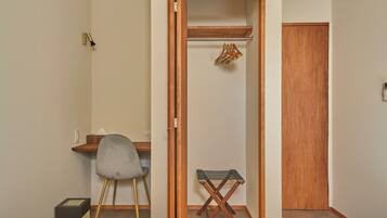 Une chambre d’hôtel comprenant un lit, un bureau avec une chaise, une armoire en bois et une petite table avec une chaise.
