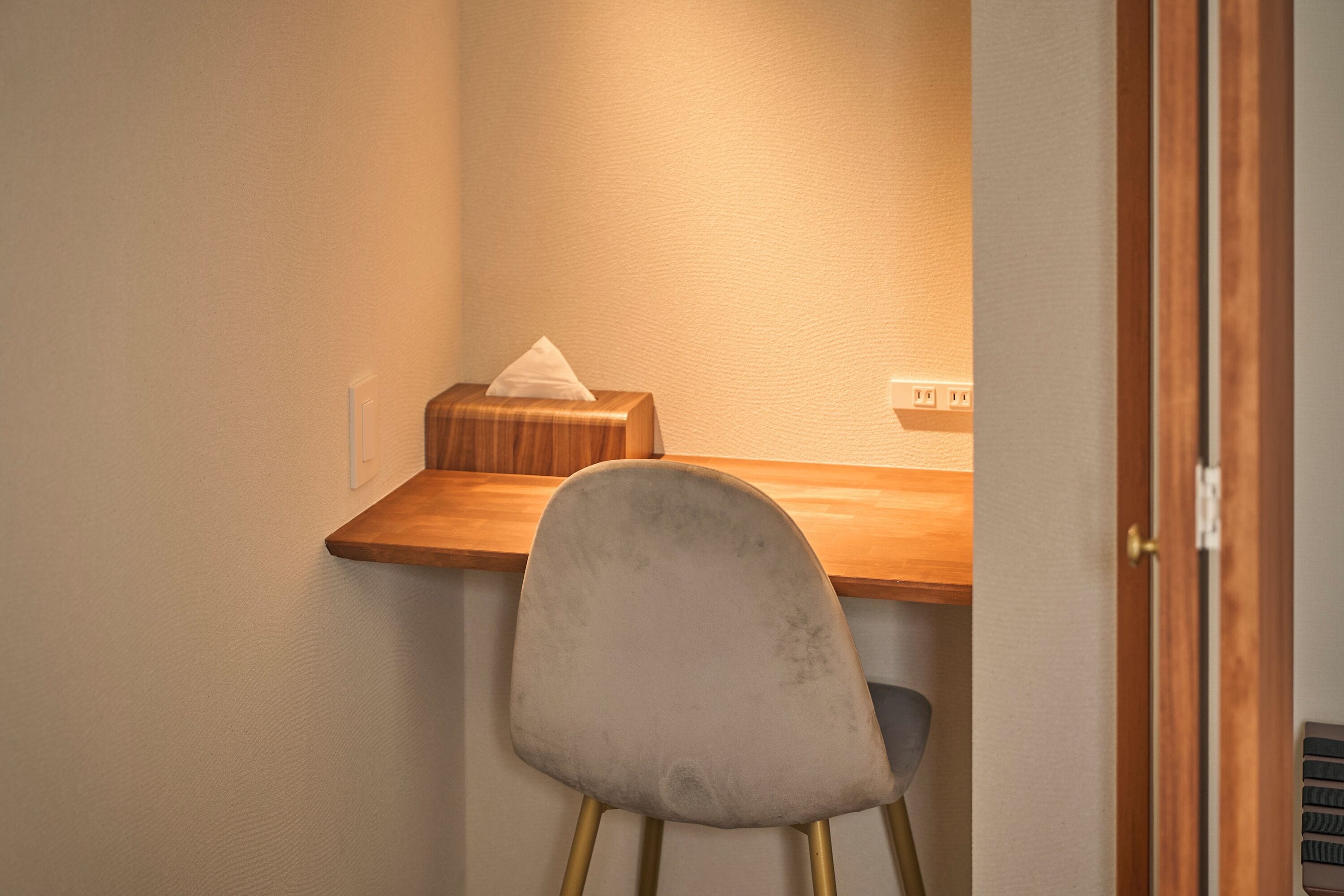 Una stanza compatta con un tavolo di legno, una sedia imbottita e un pacco di fazzoletti.