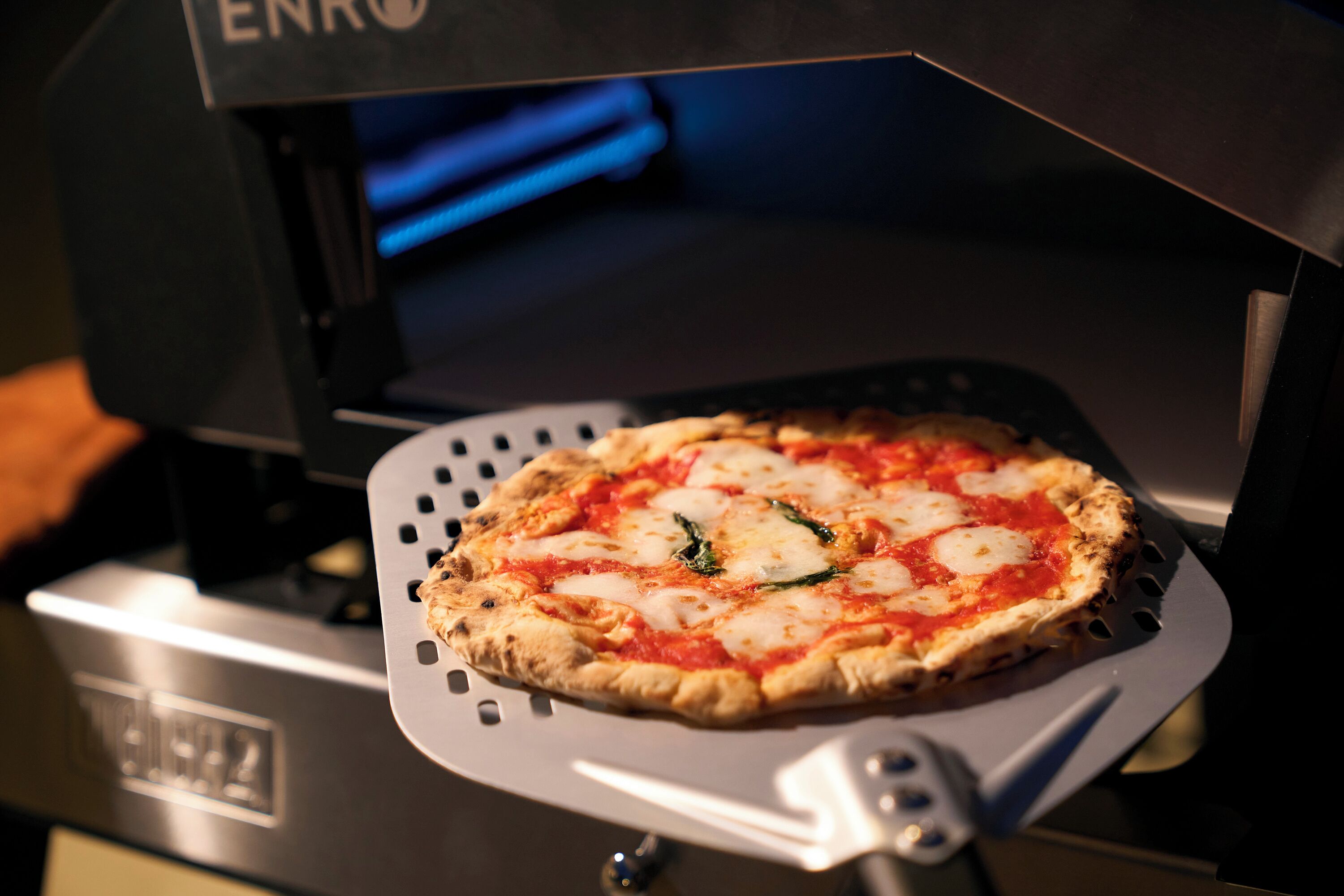 Une pizza sur une plaque en métal à l’intérieur d’un four.