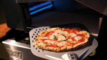 Une pizza sur une plaque en métal à l’intérieur d’un four.