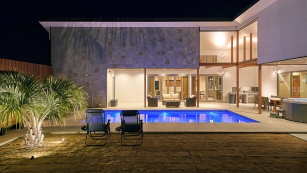 Une maison moderne dotée d’une piscine, d’un espace extérieur aménagé et d’un intérieur bien éclairé.