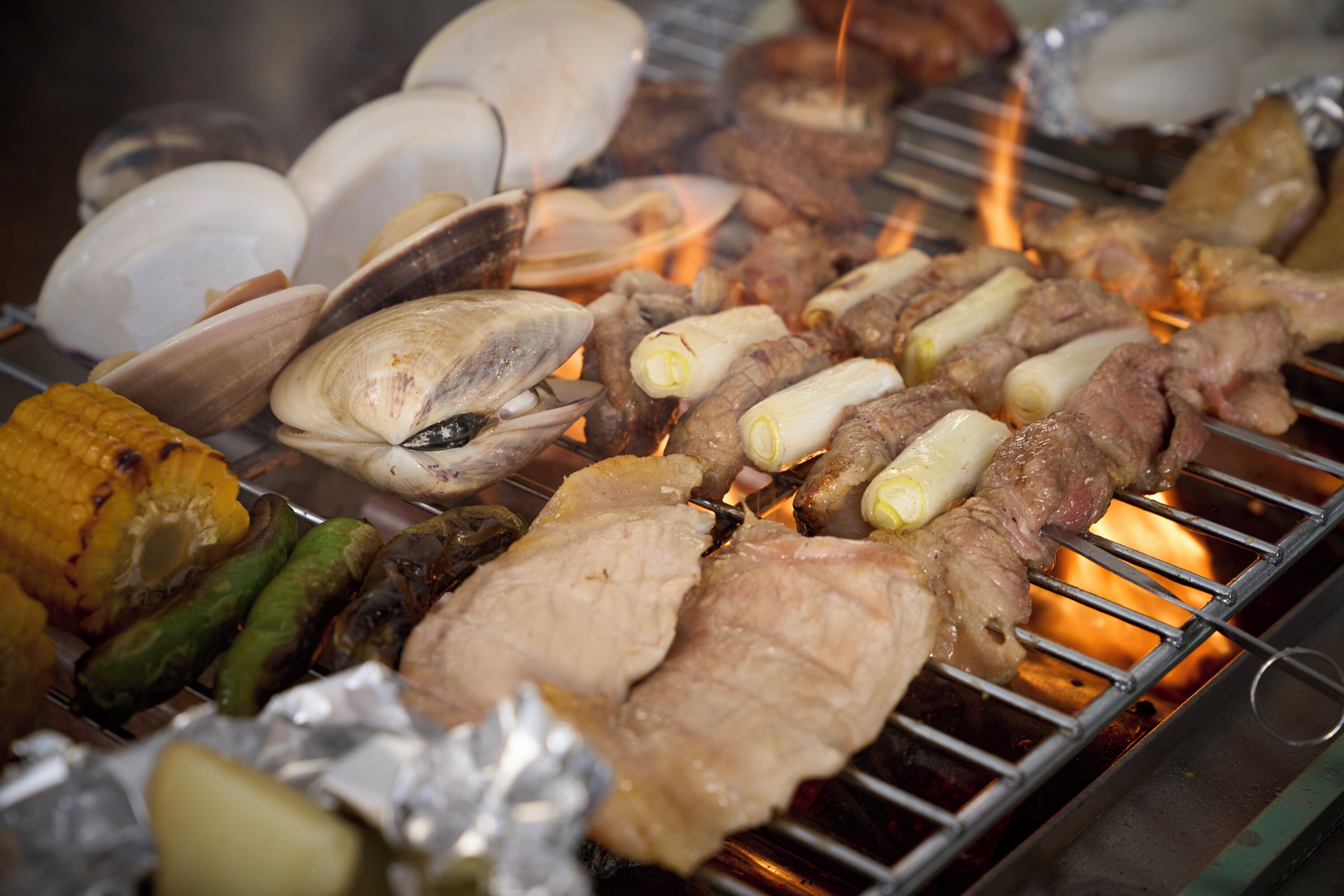 A grill with various meats and vegetables being cooked.