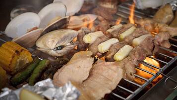 A grill with various meats and vegetables being cooked.