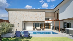Una casa moderna con piscina, mobiliario exterior y un amplio ventanal que da a un patio.