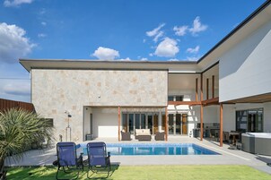Una casa moderna con piscina, mobiliario exterior y un amplio ventanal que da a un patio.