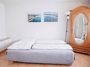 Une chambre à coucher avec un lit, une armoire en bois et deux tableaux encadrés accrochés au mur.