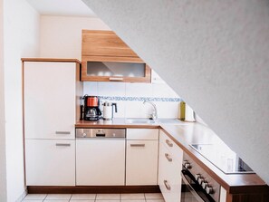 Une cuisine compacte équipée d’un lave-vaisselle, d’une machine à café et d’une cuisinière.