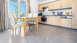 A modern kitchen with a dining area, large windows, and a view of the outdoors. - Holiday Apartment 'Am Hochufer - First Row' with Sea View, Balcony and Wi-Fi (Sellin)