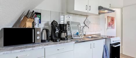 Une cuisine moderne dotée de meubles blancs, d’un four à micro-ondes, d’une machine à café, d’un grille-pain et d’un lave-vaisselle.