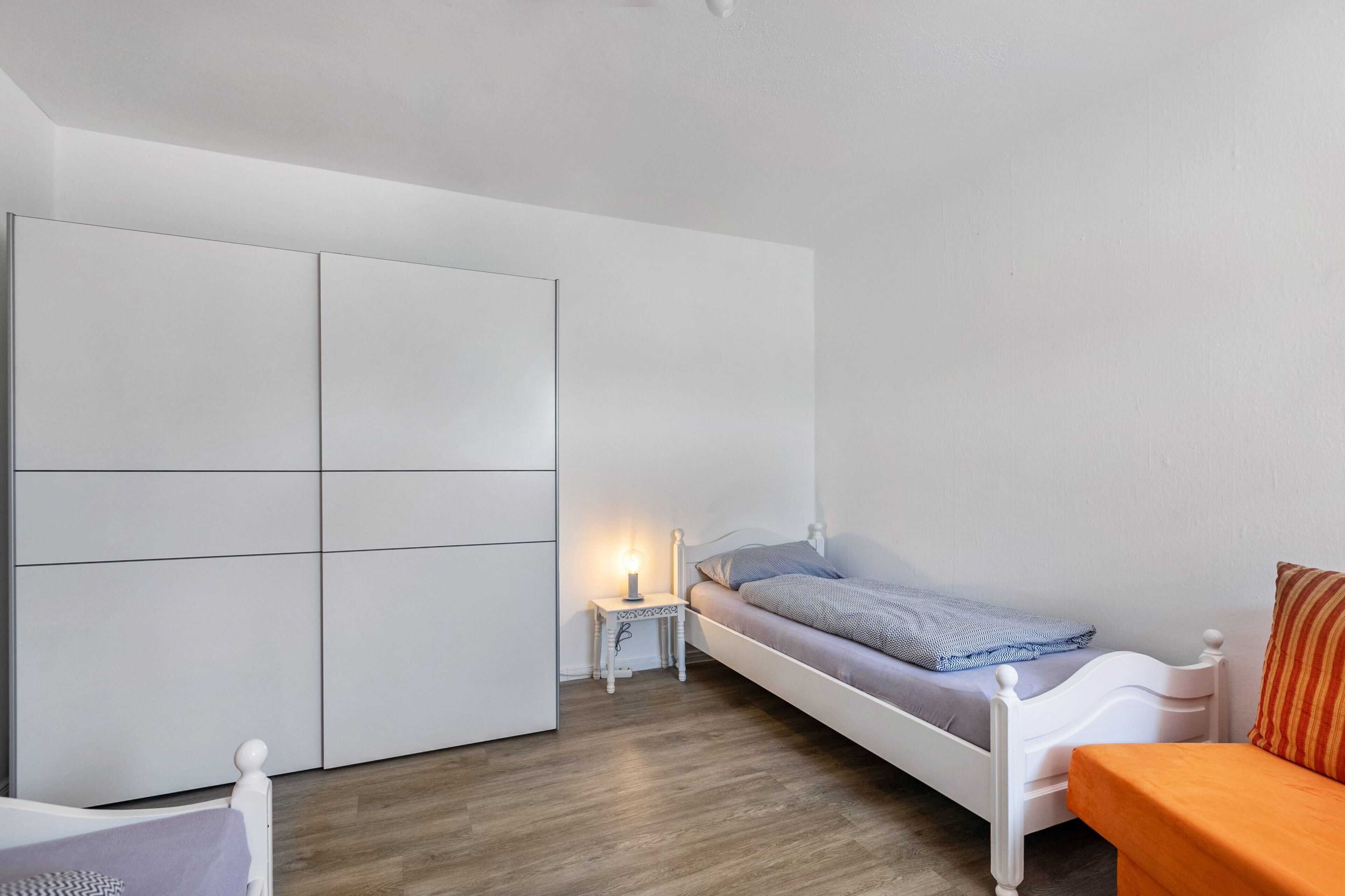 A bedroom with a bed, a nightstand, a wardrobe, and a small table.