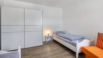 A bedroom with a bed, a nightstand, a wardrobe, and a small table.