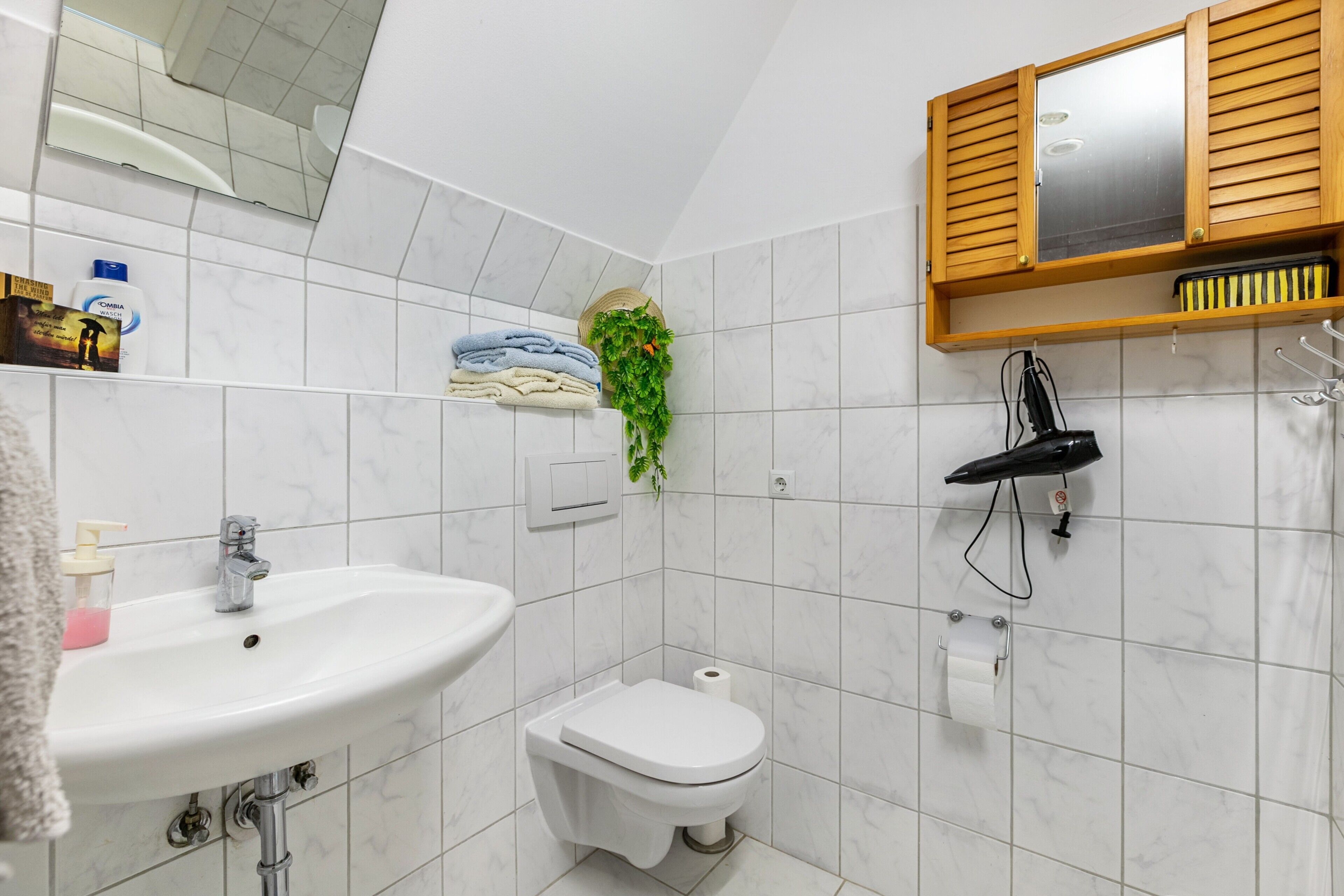 Un baño con lavamanos, inodoro, espejo y mueble de madera.