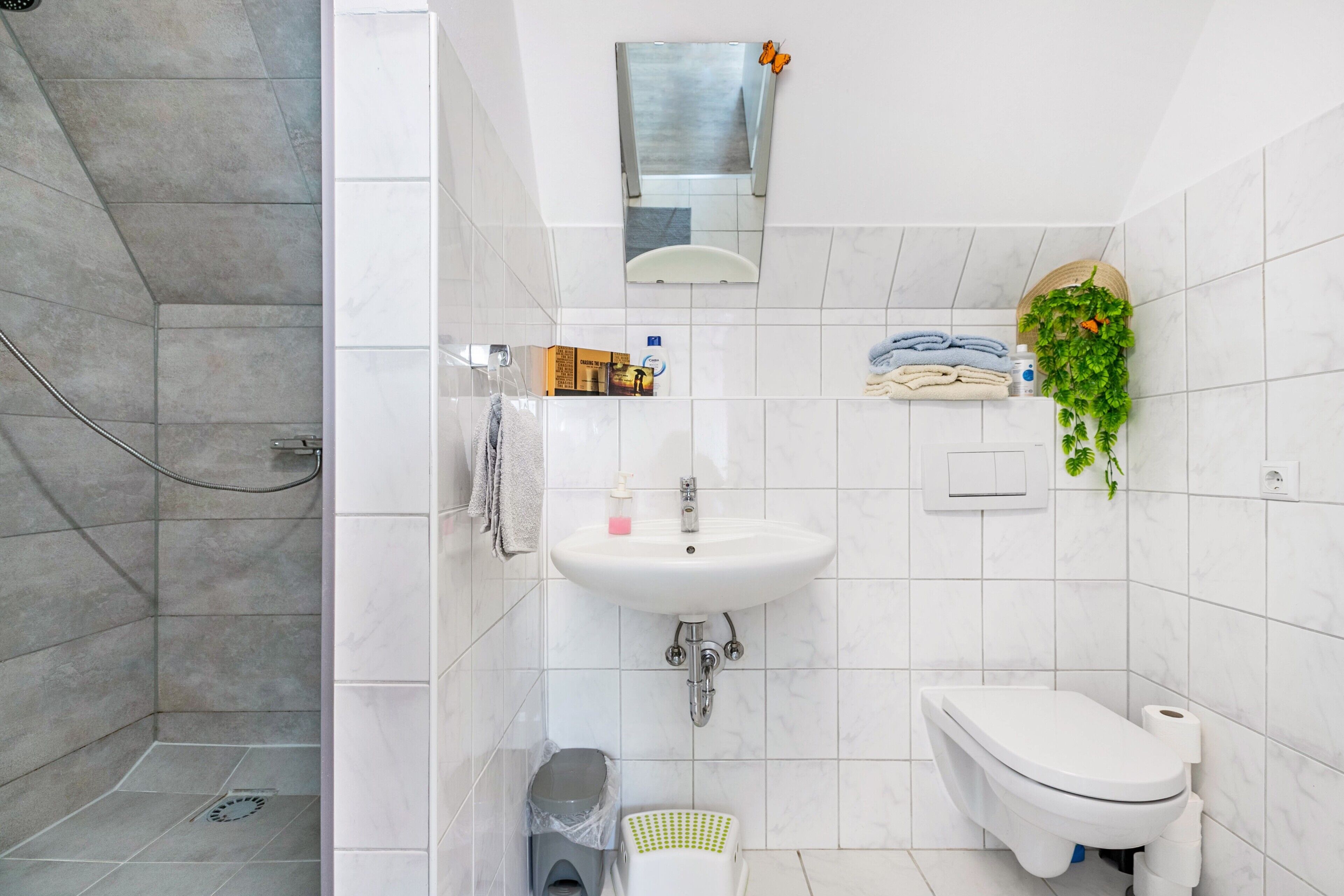 Une salle de bain moderne équipée d’une douche, d’un lavabo, de toilettes et d’une petite poubelle.