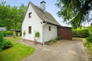A white house with a brown roof, a chimney, and a wooden garage door.