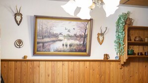A room with a wooden paneled wall, a framed landscape painting, a deer head, a shelf with pottery, and a door with a circular handle. - Holiday Home 'Carpin' with Private Terrace, Garden and Wi-Fi (Carpin)