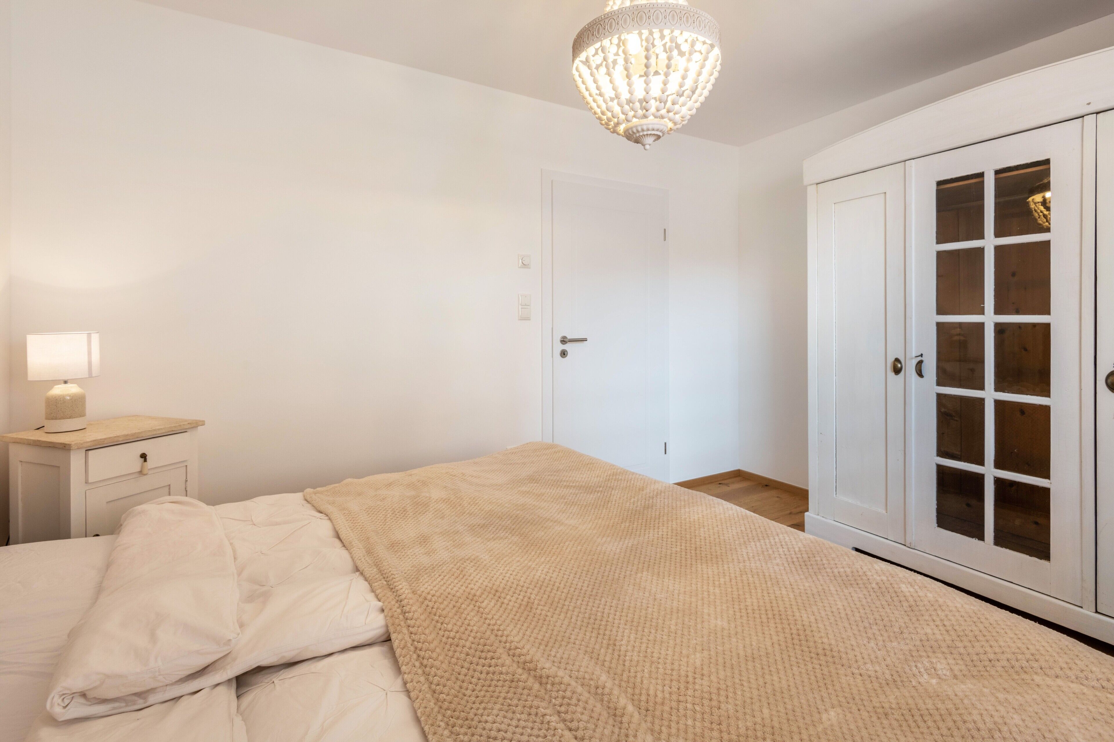 Une chambre à coucher comprenant un lit, une table de chevet, une lampe et une armoire aux portes en verre.