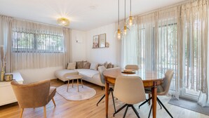 A modern living room with a sofa, dining table, chairs, and a decorative light fixture. - Apartment 'Bei Thérèse' with Private Terrace and Wi-Fi (Miltach)