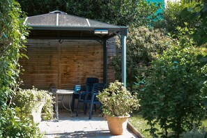 Un espace extérieur abrité, avec un mur en bois, une table et des chaises.