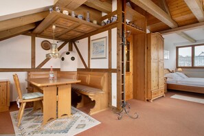 Een kamer met een houten bankje, een tafel, een hanglamp, een kledingkast en een bed.