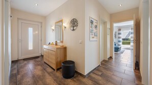 A hallway with a wooden cabinet, a black trash bin, a wall-mounted mirror, and a framed picture. - Apartment 'Sunny' with Private Terrace, Private Garden and Wi-Fi (Beckdorf)