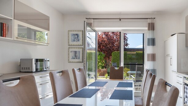 A modern kitchen with a dining area, a built-in microwave, and a view of the garden. - Apartment 'Sunny' with Private Terrace, Private Garden and Wi-Fi (Beckdorf)