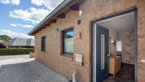 A brick building with a door leading to a room with a wooden cabinet and a small statue. - Apartment 'Sunny' with Private Terrace, Private Garden and Wi-Fi (Beckdorf)