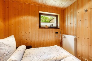 A wooden-paneled room with a bed, a window with a view, and a radiator. - Apartment 'Panoramablick' with Shared Terrace, Shared Garden and Wi-Fi (Schmallenberg)