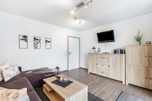 A modern living room with a sofa, a coffee table, a flat-screen TV, and wooden cabinets.