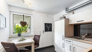 Een moderne keuken met witte kasten, een roestvrijstalen spoelbak en een raam met uitzicht op groen.