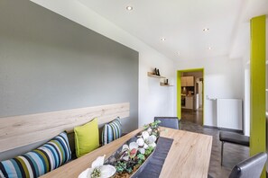 Un espace repas moderne avec une longue table en bois, un banc et diverses plantes décoratives.