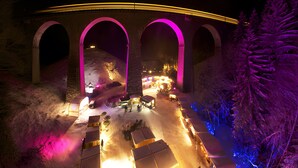 Un puente con arcos, suelo cubierto de nieve y tiendas de campaña instaladas debajo del puente.