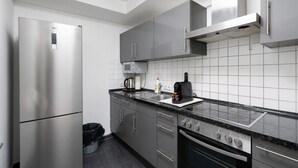 A modern kitchen with stainless steel appliances, grey cabinets, and a black countertop. - Holiday Apartment 'Aldars 15' with Wi-Fi and Air Conditioning (München)
