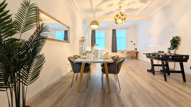 A modern living room with a dining area, a foosball table, and a large mirror.