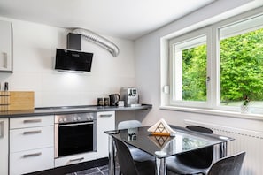 Cocina moderna con horno empotrado, cafetera y ventana con vistas a zonas verdes.