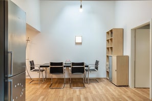 A modern kitchen with a dining table, four chairs, a refrigerator, and a wooden cabinet.