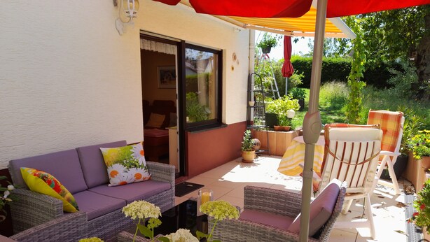 Un patio con mobiliario de mimbre, un sofá y plantas en macetas.