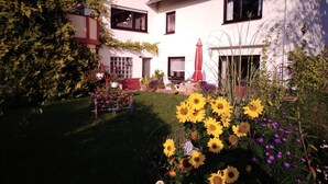 Una casa con jardín, paneles solares y un paraguas rojo.