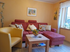 A living room with a sofa, armchair, and a small table with a vase of flowers.