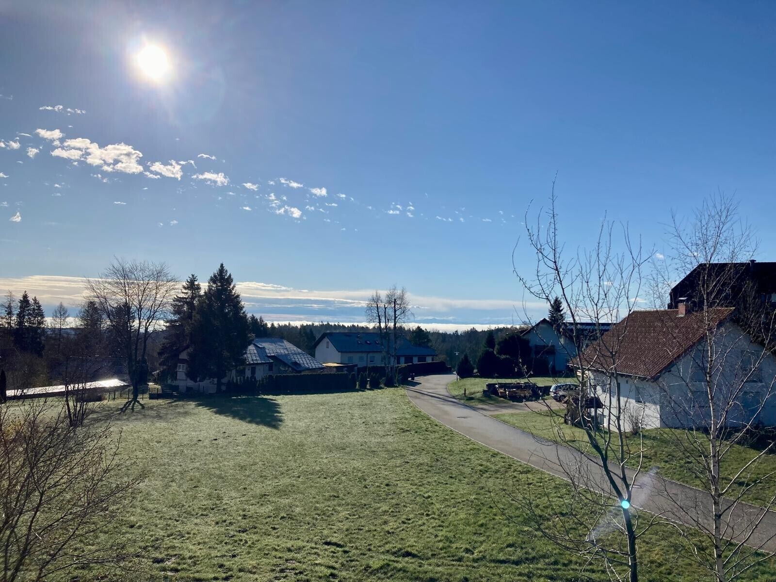 Paisaje rural con casas, cielo despejado y un camino.