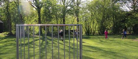 A playground with a metal play structure and a soccer ball on the grass.