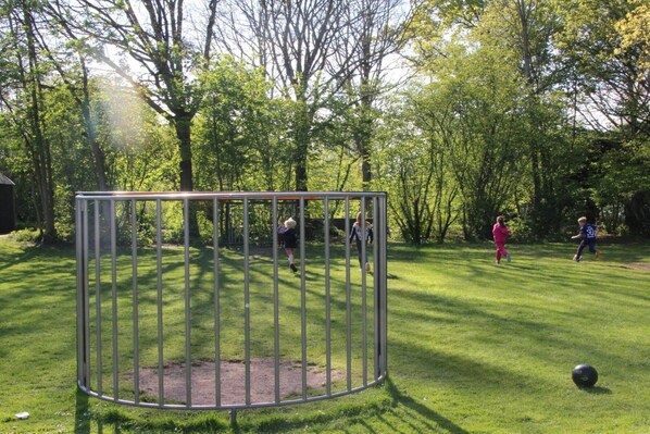 A playground with a metal play structure and a soccer ball on the grass.